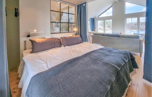 Cozy Home In Uddevalla With House Sea View في Sundsandvik: غرفة نوم بسرير كبير في غرفة بها نوافذ