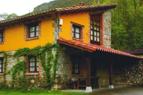 a yellow house with ivy growing on the side of it at La Rotella, calma al lado de Cangas de Onís in Cangas de Onís