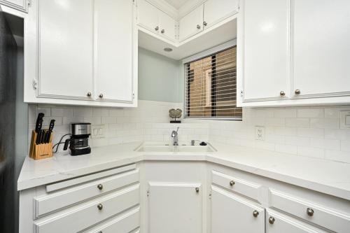 a white kitchen with white cabinets and a sink at Multi Level Oceanfront Home With Oceanviews and Private Patio on the Boardwalk in Newport Beach