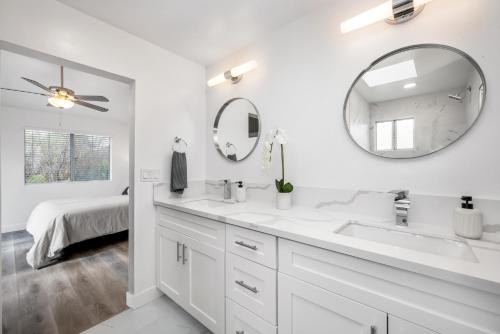 Baño blanco con 2 lavabos y espejo en Spacious Home with 7 Beds minutes from Mission Bay, en San Diego