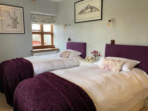 two beds in a room with purple and white at White House Farm 