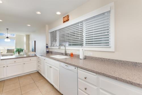 cocina con armarios blancos, fregadero y ventana en Multi Level Oceanfront Home With Oceanviews and Private Patio on the Sand, en Newport Beach