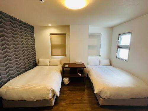 two beds in a room with a table and windows at Mr,KINJO in RYCOM Kitanakagusuku - Vacation STAY 59274v in Shimabuku