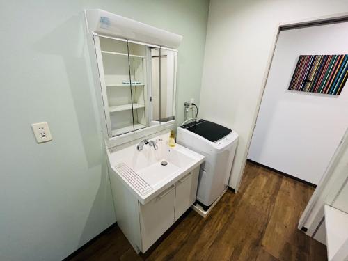 Baño blanco con lavabo y espejo en Mr,KINJO in RYCOM Kitanakagusuku - Vacation STAY 59274v, en Shimabuku