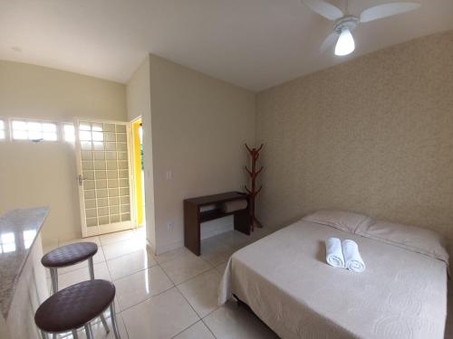 1 dormitorio con 1 cama, 1 mesa y 2 taburetes en Chalé Cipó Maia, en Serra do Cipo