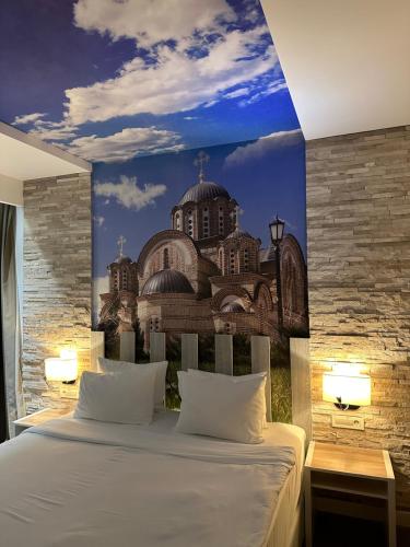 a bedroom with a bed with a painting of a building at Hotel Nar in Trebinje