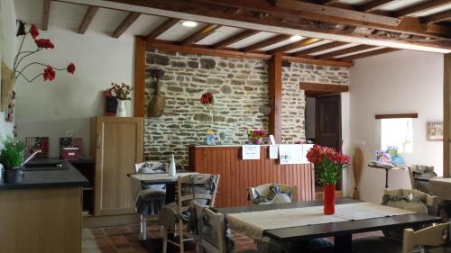comedor con mesas y sillas y pared de piedra en La Bastide du Moulin - Mont St Michel, en Moidrey