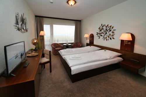 a bedroom with a bed and a desk and a television at Strandhotel Salty in Büsum