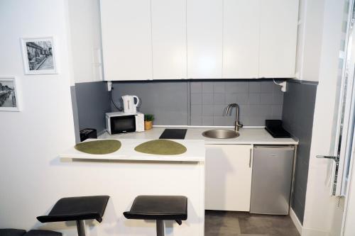 a kitchen with white cabinets and a sink and stools at Eiffel Tour Cosy Oliver in Paris