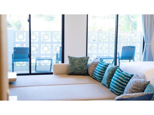 ein Wohnzimmer mit einem Sofa mit Kissen darauf in der Unterkunft Hotel Torifito Miyakojima Resort - Vacation STAY 79484v in Miyako-jima