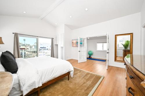 a white bedroom with a bed and a large window at Sunset Island Waterfront Home with Kayaks across the Street from the Beach in Sunset Beach