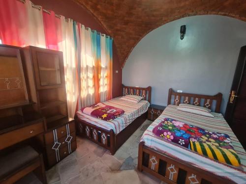2 camas en una habitación con cortinas y un piano en Nubian Magic villa, en Nag` el-Ramla