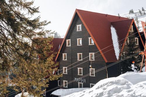 a large black building with a red roof in the snow at Маріна Драгобрат in Dragobrat