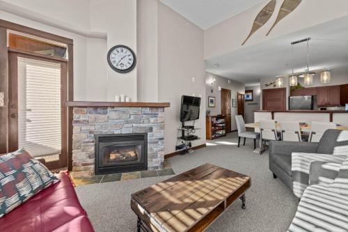 a living room with a fireplace and a clock on the wall at Stones Throw #26 By Bear Country in Sun Peaks