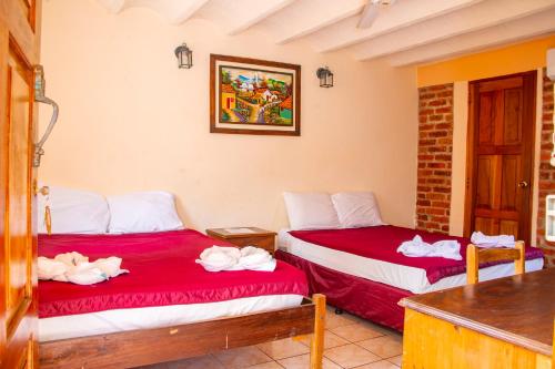 2 camas en una habitación con sábanas rojas y blancas en VÉLEZ Beach Hotel, en San Juan del Sur