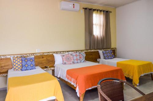 a hotel room with two beds with colorful sheets at Hotel Pousada Rei do Suco in Olímpia