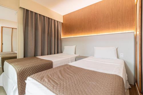 a hotel room with two beds and a window at H4 Fortune Jardins in Sao Paulo