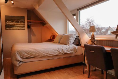 1 dormitorio con cama, escritorio y ventana en B&B Zee-en-Zo, en Noordwijk