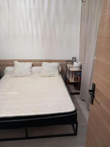 un lit avec des draps blancs et des oreillers dans une chambre dans l'établissement location appartement Berck 350 m de la plage, à Berck-sur-Mer