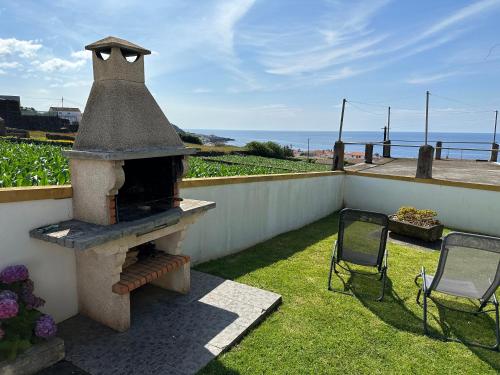a patio with an outdoor oven with two chairs at Casa do Alemao in Porto Judeu