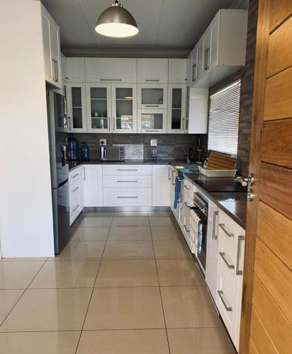 uma grande cozinha com armários e electrodomésticos brancos em Spacious Private room em Windhoek