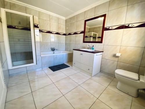 uma casa de banho com uma banheira, um lavatório e um WC. em Spacious Private room em Windhoek