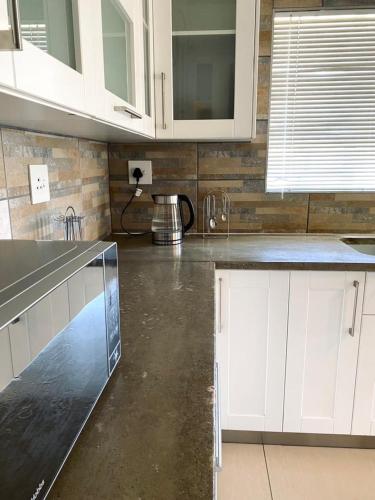 a kitchen with white cabinets and a concrete floor at Spacious Private room in Windhoek