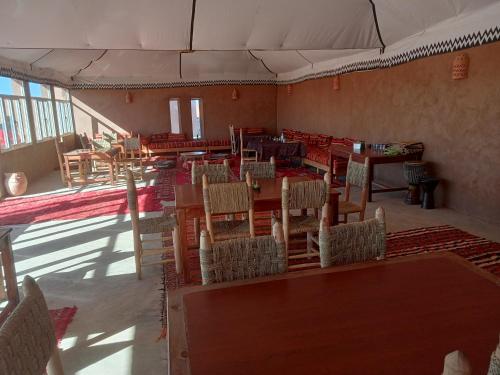 um restaurante vazio com mesas e cadeiras num quarto em Couleur du désert em Mhamid
