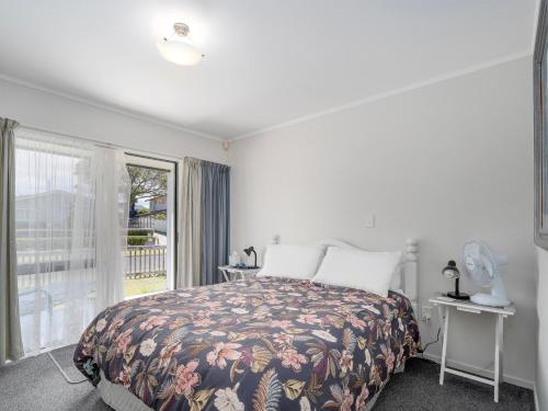 a bedroom with a bed and a large window at Beach Life - Whangamata Holiday Home in Whangamata