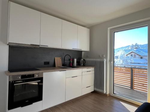 a kitchen with white cabinets and a large window at Haus Bergblick in Villach
