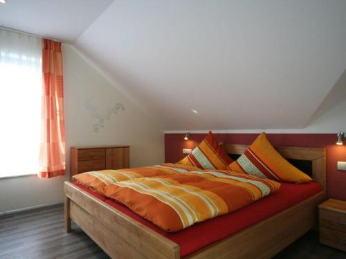 a bedroom with a large bed with orange and yellow sheets at Strandhus Sellin - House 1 in Ostseebad Sellin