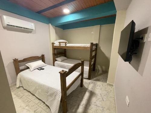a room with two bunk beds and a tv at Villa Carolina SM in Santa Marta