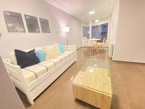ein Wohnzimmer mit einem weißen Sofa und einem Tisch in der Unterkunft Depto Nueva Cordoba Guemes in Cordoba