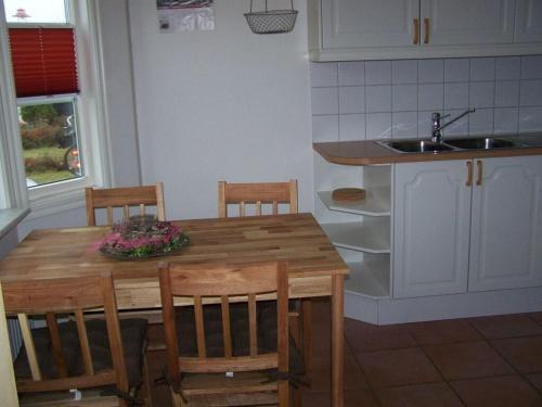 een keuken met een houten tafel met stoelen en een wastafel bij Schwedenhaus Grüner Weg in Burg auf Fehmarn
