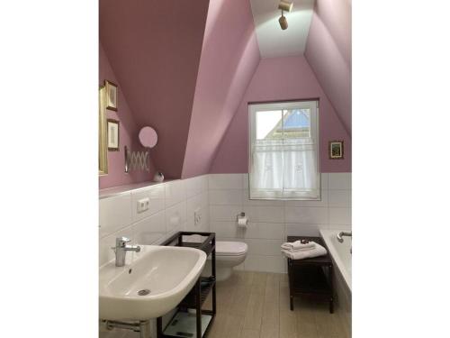 baño con paredes de color púrpura, lavabo y ventana en Susi and Strolchis, en Zierow
