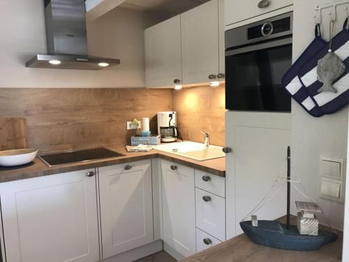 a kitchen with white cabinets and a black microwave at Holiday apartment Nordwind in Wrixum