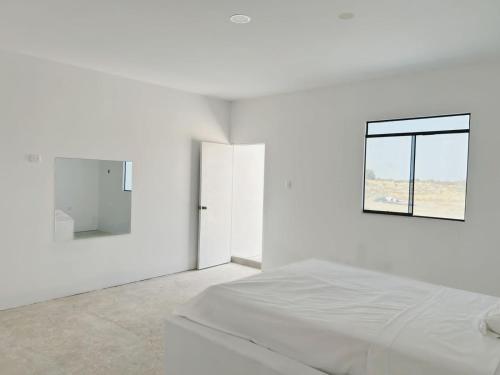 a white bedroom with a bed and a window at fundo los merino in Milla 7