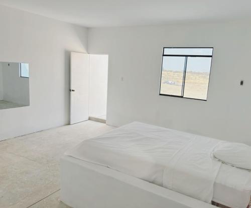 a white bedroom with a bed and a window at fundo los merino in Milla 7