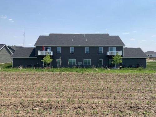 a large black house with a field in front of it at Main Floor 2 Bedroom Condo in Bettendorf in Bettendorf