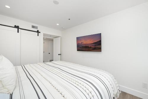 a white bedroom with a bed with a painting on the wall at Perfect Renovated and Modern Duplex on Balboa Island in Newport Beach