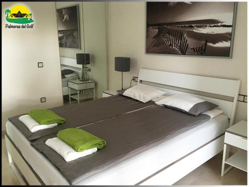 1 dormitorio con 1 cama grande con almohadas verdes en Palmeras del Golf - Torrequebrada, en Benalmádena