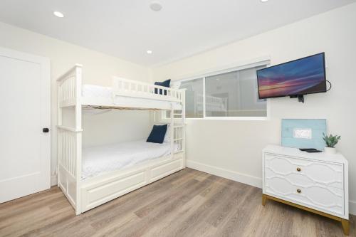 a white bedroom with a bunk bed and a tv at 3 Bedroom Renovated Condo on Balboa Island in Newport Beach