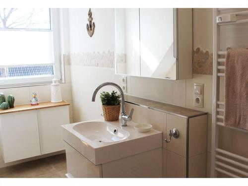 een witte badkamer met een wastafel en een raam bij Cosy apartment near centre in Langeoog