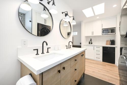 a white bathroom with a sink and two mirrors at 4 bedroom Renovated Home on Balboa Island in Newport Beach