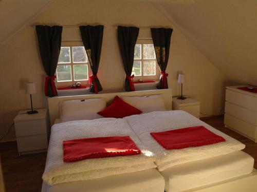 um quarto com uma grande cama branca com almofadas vermelhas em Rauchkate Weibeck em Hessisch Oldendorf
