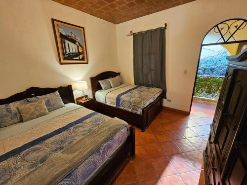 a bedroom with two beds and a large window at La Capitanía de San Pedro in Antigua Guatemala