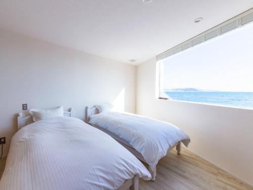 a white bedroom with a bed and a large window at URBAN & BEACH - Vacation STAY 74389v in Awaji