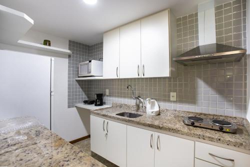 a kitchen with white cabinets and a sink at Apartamento a 500 m da Praia de Itacoatiara in Niterói