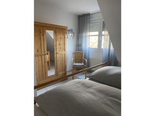 een slaapkamer met een bed, een spiegel en een stoel bij Holiday house house sound of the sea in Borkum