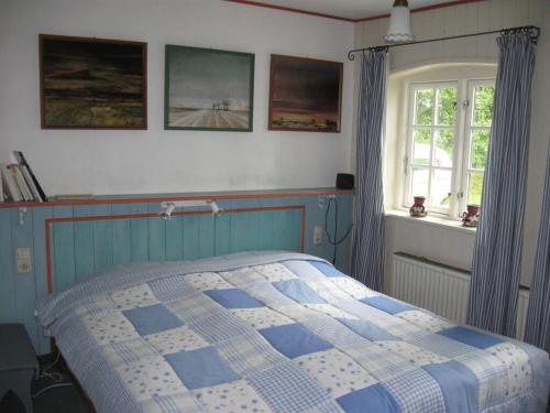 a bedroom with a blue and white bed and a window at Romantic thatched roof house in Schnarup-Thumby